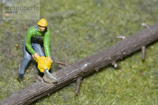 Figur eines Holzfällers  der Baumstamm mit elektrischer Säge schneidet