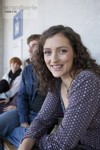 Frau lächelt mit Studenten im Hintergrund