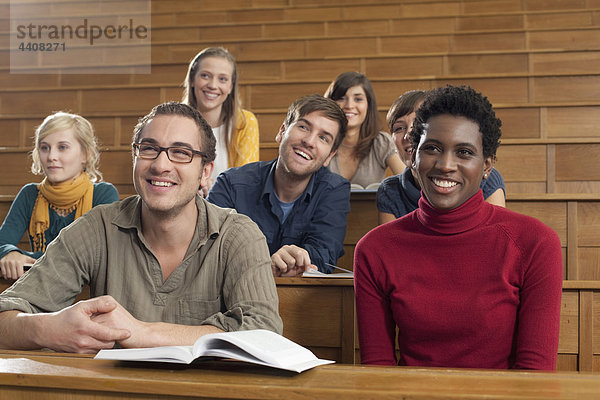 Deutschland  Leipzig  Gruppe von Studenten  die im Klassenzimmer studieren  lächelnd