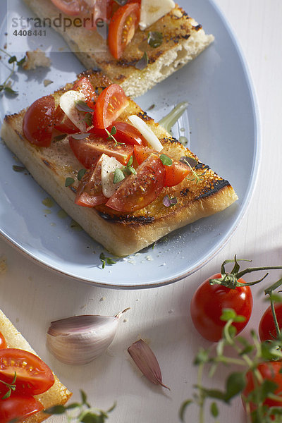 Ciabatta-Brot mit Tomatenscheiben und Zwiebeln im Teller.