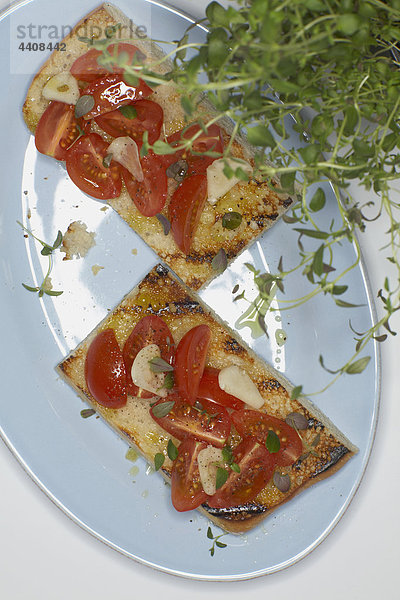 Ciabatta-Brot mit Tomatenscheiben und Zwiebeln im Teller.