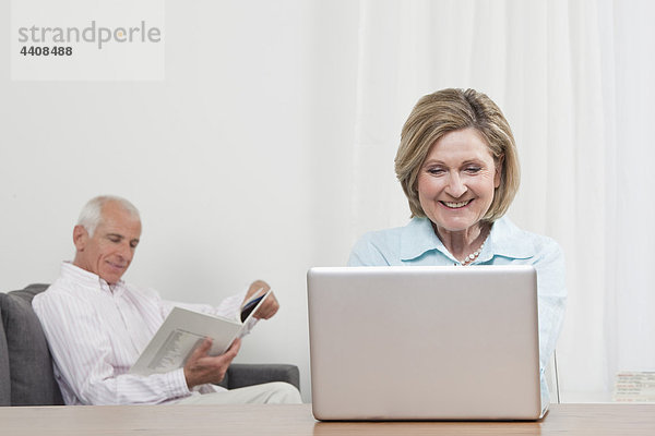 Frau mit Laptop und Mann im Hintergrund