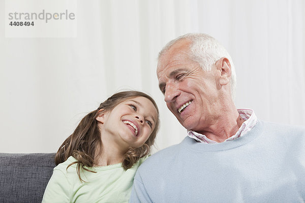 Großvater und Enkelin (6-7) schauen sich an und lächeln.