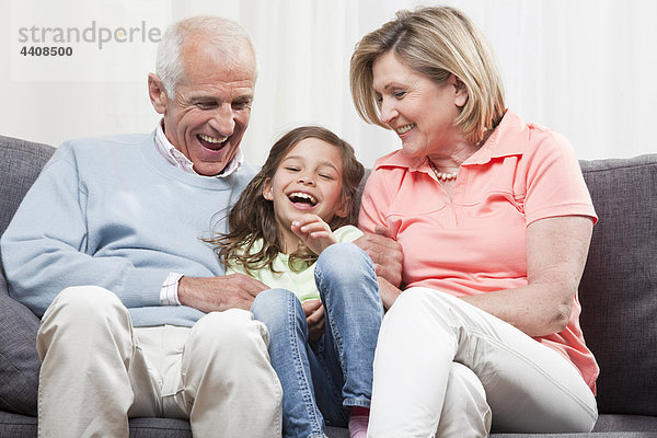 Enkelin (6-7) und Großeltern sitzend und genießend  lächelnd
