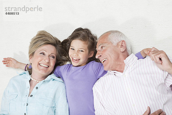 Enkelin (6-7) liegend mit Großeltern  lächelnd