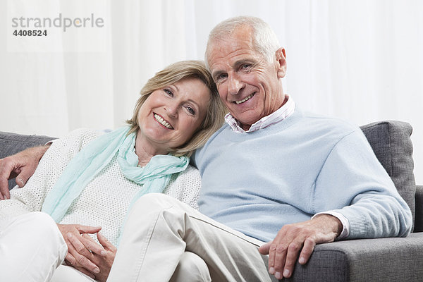 Seniorenpaar auf Couch sitzend  lächelnd  Portrait