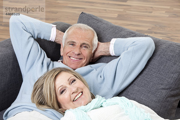 Seniorenpaar auf der Couch liegend  lächelnd  Portrait