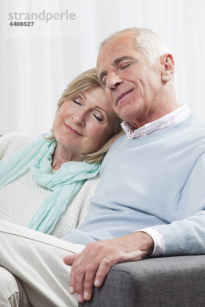 Seniorenpaar auf Couch sitzend  lächelnd  Augen geschlossen