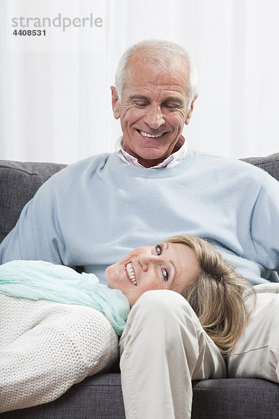 Mann sitzend mit Frau auf dem Schoß liegend  lächelnd