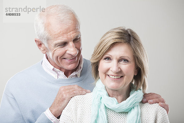 Seniorenpaar vor grauem Hintergrund  lächelnd