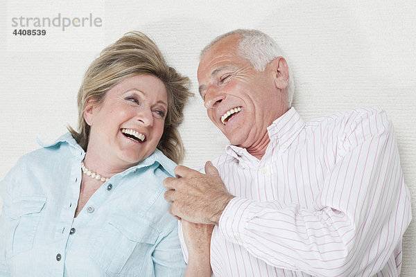 Seniorenpaar hält sich an den Händen und lächelt.