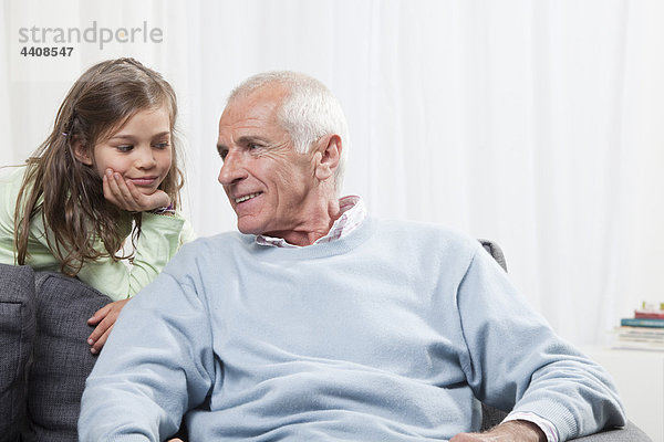 Enkelin (6-7) mit dem Kopf in der Hand  die dem Großvater zuhört.