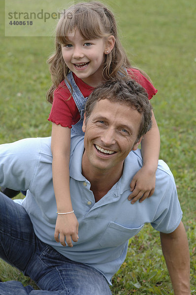 Vater und Tochter spielen im Garten  Porträt  lächeln.