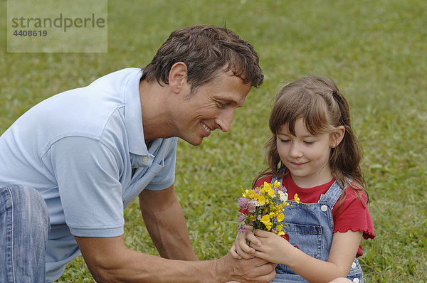 Vater schenkt der Tochter Blumen  lächelnd