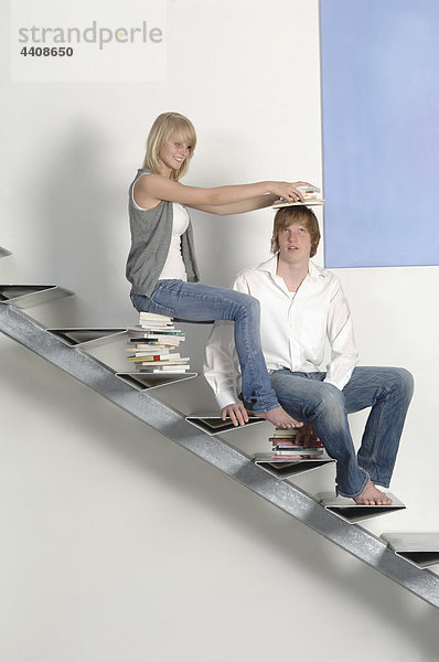 Teenager-Paar auf der Treppe sitzend mit Bücherstapel