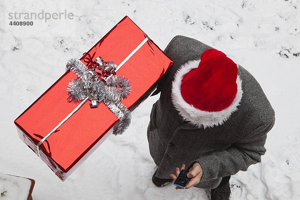 Mann mit Weihnachtsgeschenk und Handy