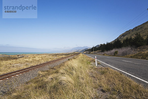 Neuseeland  Südinsel  Canterburg  Kaikoura  Blick auf die Hauptstraße mit Eisenbahnschienen und Meer im Hintergrund
