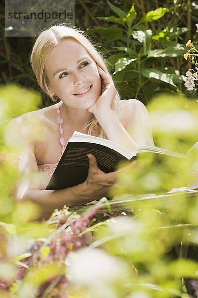 Österreich  Frau im Garten Lesebuch  lächelnd