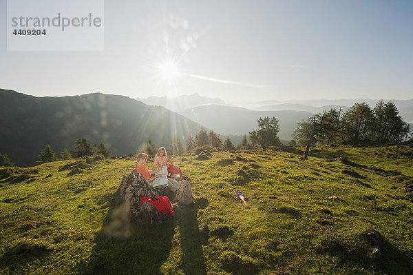 Ein junges Paar  das sich eine Karte auf einem Berggipfel ansieht.