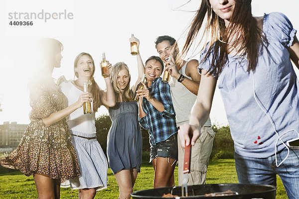 Frau beim Grillen mit Freunden im Hintergrund