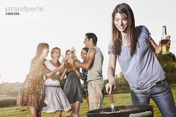 Frau beim Grillen mit Freunden im Hintergrund