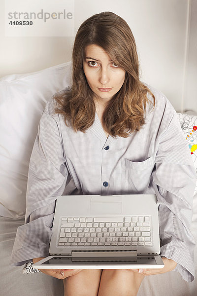 Frau auf dem Bett sitzend mit Laptop  erhöhte Ansicht