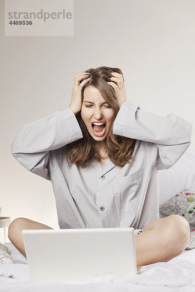 Frau mit Laptop und Kopf in der Hand  schreiend