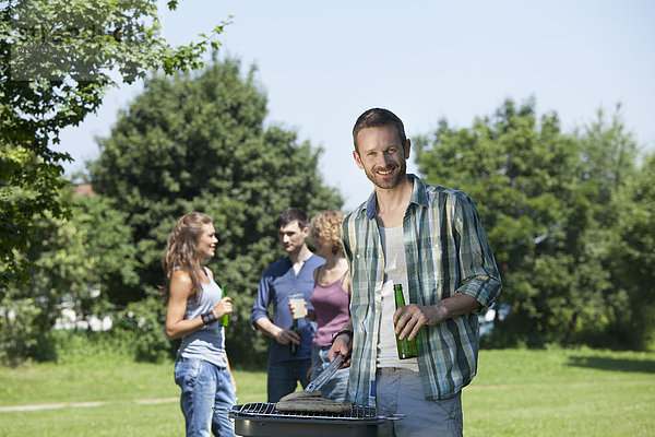 Mann kocht Essen und Freunde im Hintergrund