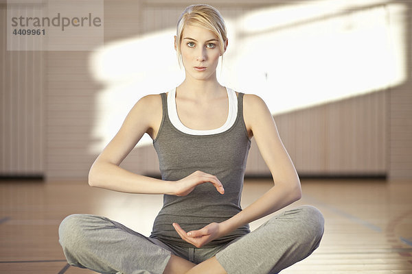 Frau sitzend in Yoga-Pose auf Übungsmatte  Portrait