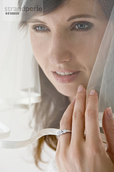 Nahaufnahme der Braut  die ihren Ehering zeigt  schaut wegSchließt die Braut  die ihren Ehering zeigt  schaut weg