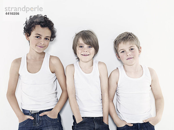 Jungen (8-11) stehend mit Händen in der Tasche vor weißem Hintergrund
