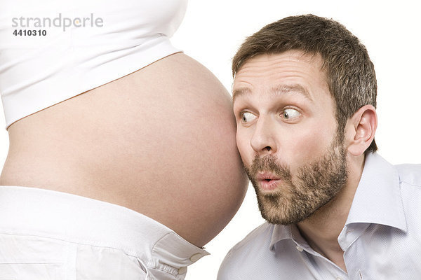 Mann hört auf den Bauch einer schwangeren Frau  Nahaufnahme