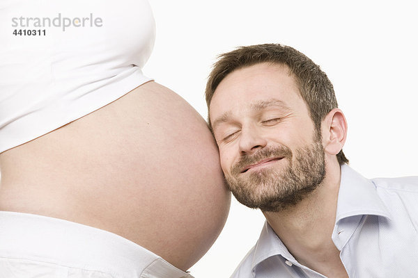 Mann hört auf den Bauch der Schwangeren  Augen geschlossen  Nahaufnahme