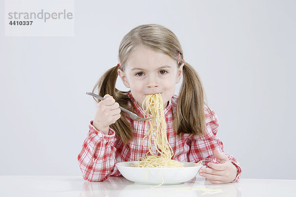 Mädchen (4-5) isst Spagetti  lächelnd  Portrait