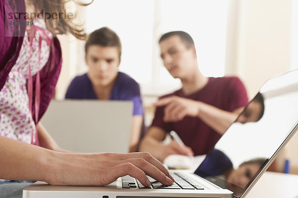 Teenage Girl mit Laptop und Schülern im Hintergrund