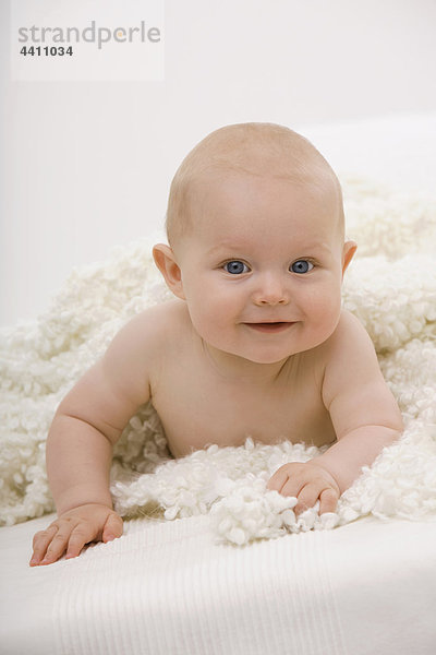 Junge (6-11 Monate) auf dem Bett liegend  lächelnd  Portrait