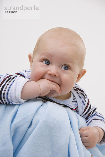 Baby Junge (6-11 Monate) mit Finger im Mund  wegschauend