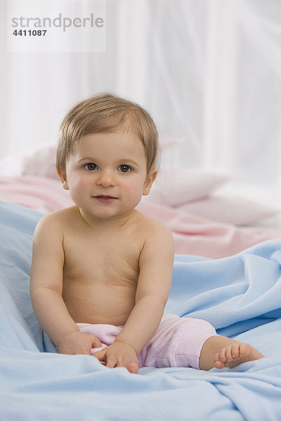 Baby Mädchen (6-11 Monate) sitzend auf Decke  Portrait