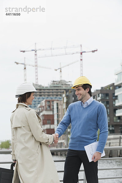 Mann und Frau mit Bauplan im Hafen