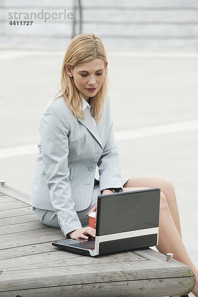 Geschäftsfrau lächelt am Hafen mit Laptop