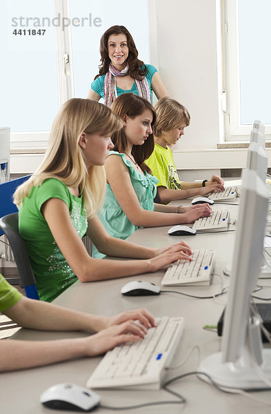 Deutschland  Emmering  Lehrer stehend mit Schülern im Computerlabor