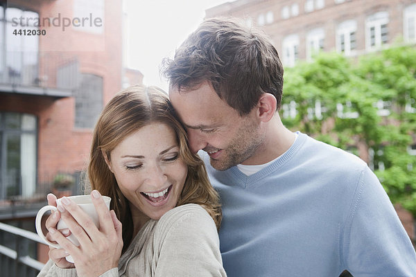 Deutschland  Paar genießt auf dem Balkon mit Frau mit Kaffeetasse