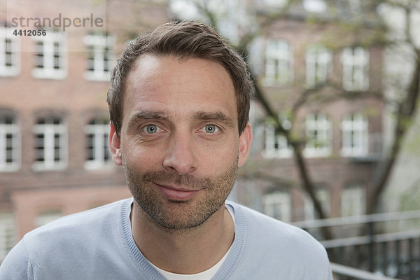 Deutschland  Porträt eines Mannes auf dem Balkon  lächelnd