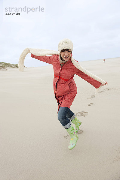 Deutschland  St. Peter-Ording  Nordsee  Frau hat Spaß in Sanddünen  lächelnd  Portrait