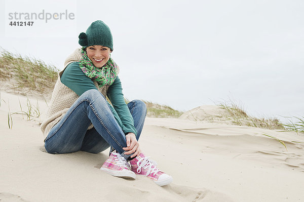 Deutschland  St. Peter-Ording  Nordsee  Frau hat Spaß in Sanddünen  lächelnd  Portrait