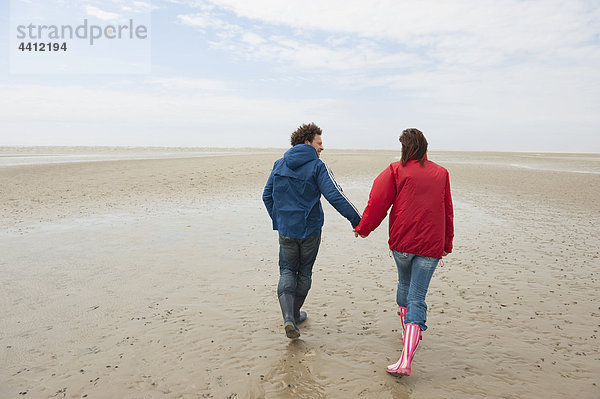 Deutschland  St. Peter-Ording  Nordsee  Paar Händchen haltend und am Strand spazierend