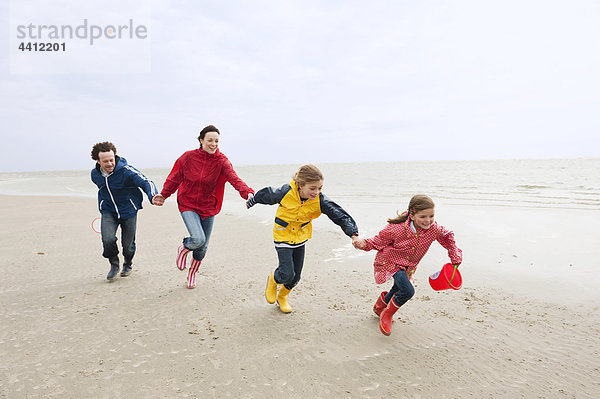 Deutschland  St. Peter-Ording  Nordsee  Familie beim Händchenhalten und Laufen am Strand