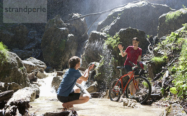 Österreich  Salzkammergut  Mondsee  Junges Paar mit Fahrrad und Wasserfall im Hintergrund