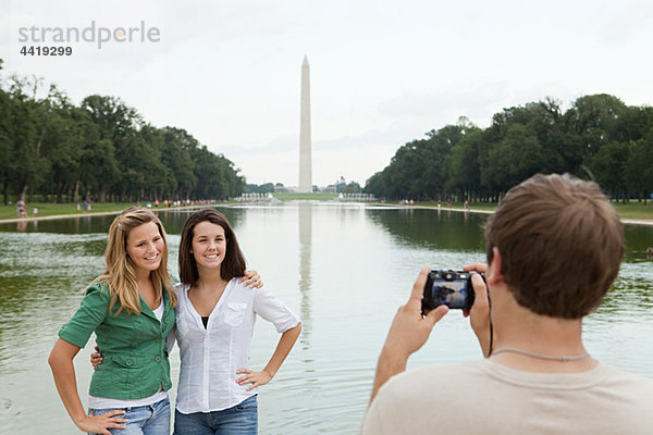 Junger Mann fotografiert Freunde am Washington Monument.