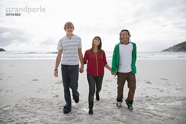Drei Menschen zu Fuß am Strand Hände